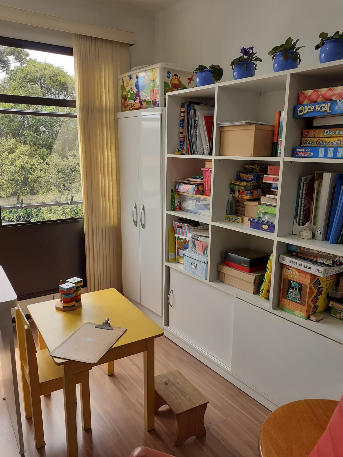 Sala de atendimento infantil do Espaço Essencia, com mesinha, jogos e estante de livros
